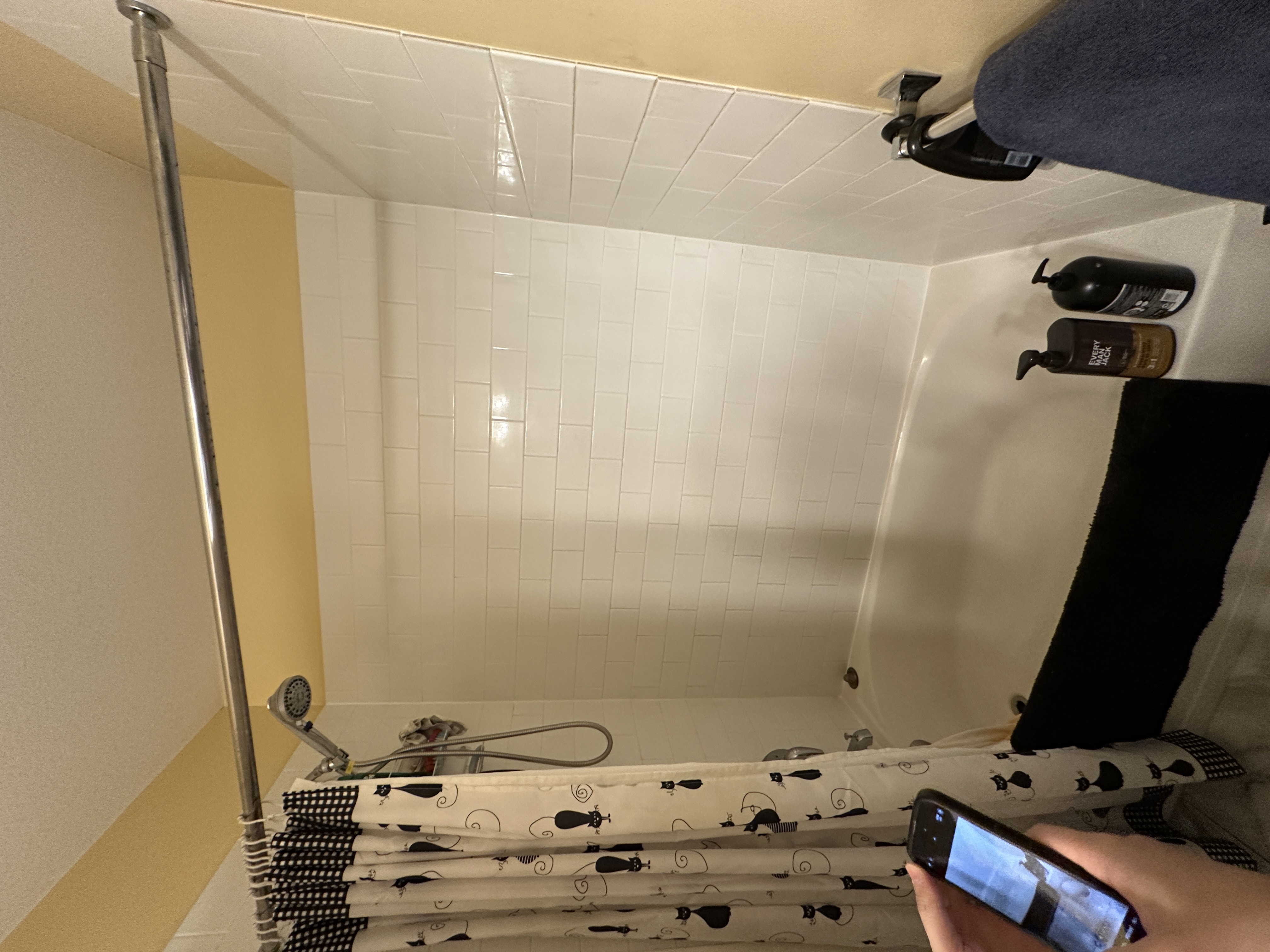Tub surround before the renovation, old white tile and a shower curtain